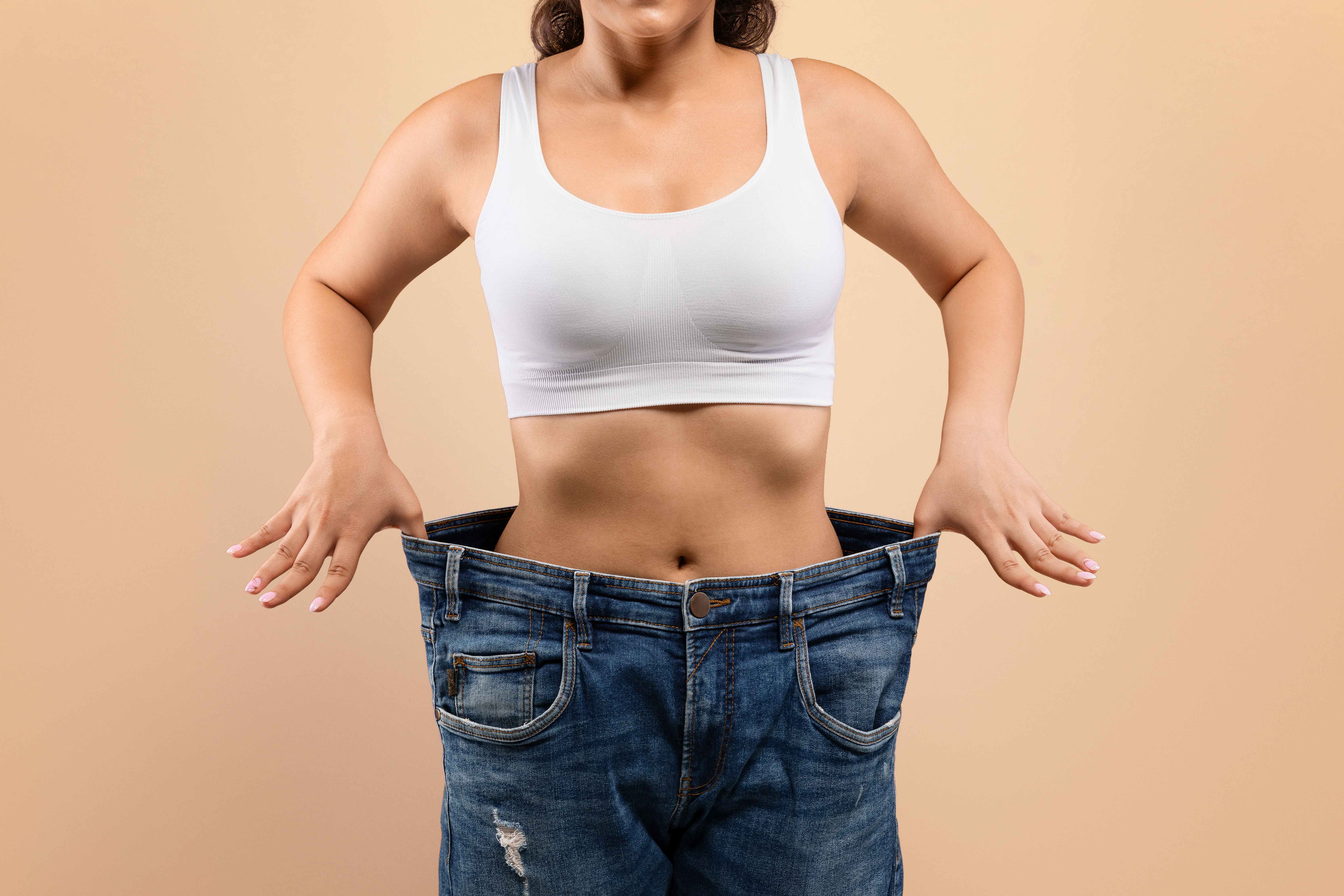successful diet. young female in oversized jeans demonstrating results of her slimming